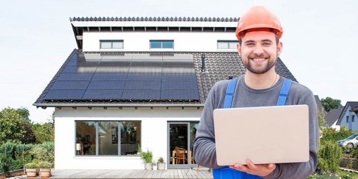 Ein Monteur mit einem Laptop der vor einer Photovoltaikanlage steht