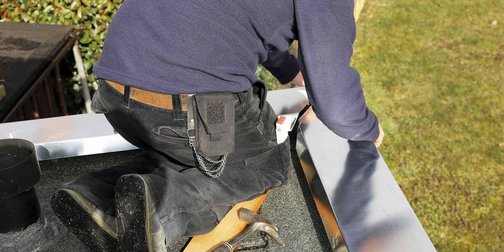 Ein Klempner der Metall auf einem Flachdach bearbeitet